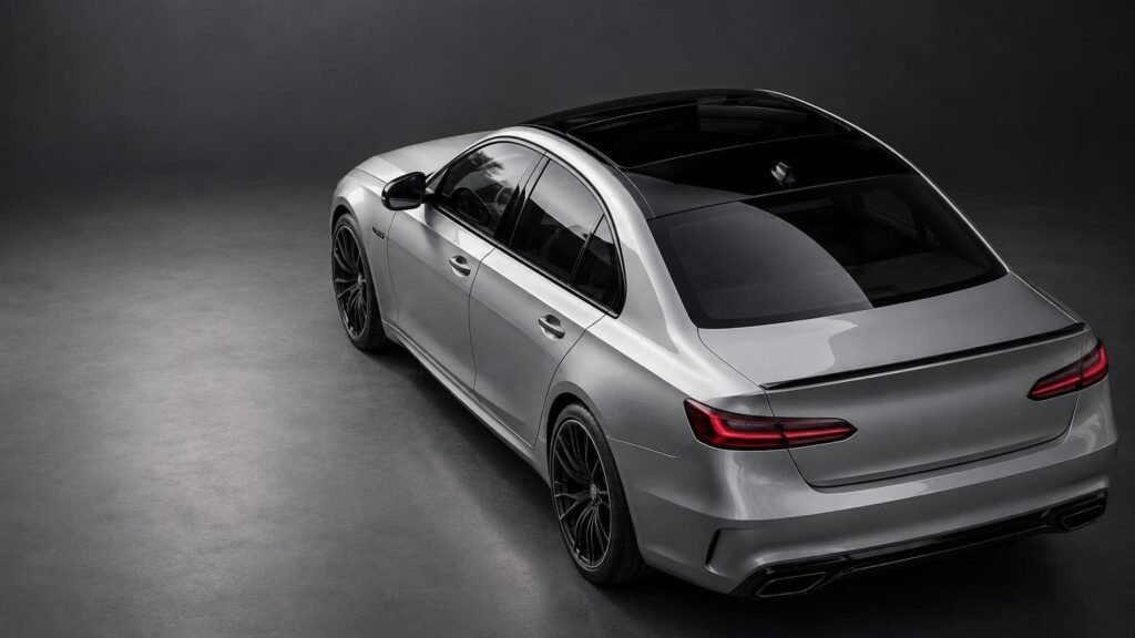 Studio-lit rear three-quarter view of a silver luxury sedan with a glossy black panoramic-style roof, dark window trim, black wheels, and red tail lights against a dark gray background.